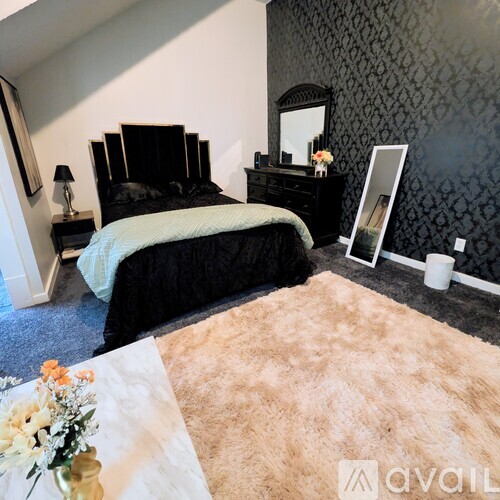 A bedroom with a black bed and a mirror on the wall.