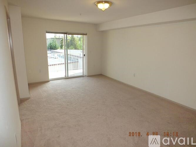 A room with a carpeted floor and a sliding glass door leading to a parking lot.