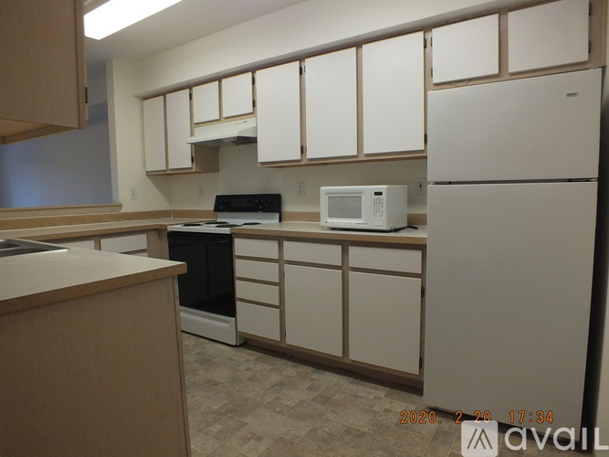 A kitchen with white cabinets and a white fridge.