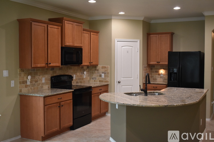 A kitchen with brown cabinets and black appliances.