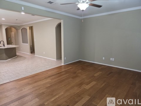 A spacious room with wooden flooring and a ceiling fan.