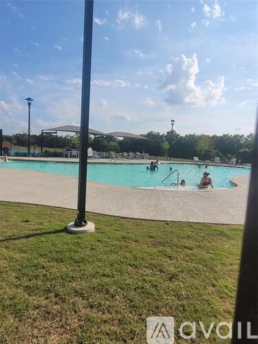 A pool with people swimming and a pole in the foreground.