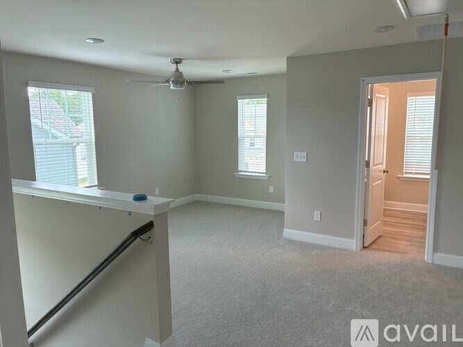 A spacious room with a ceiling fan and a door leading to another room.