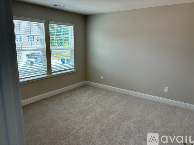 A room with a carpeted floor and a window with blinds.