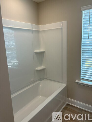 A white bathtub in a bathroom with a window on the right side.