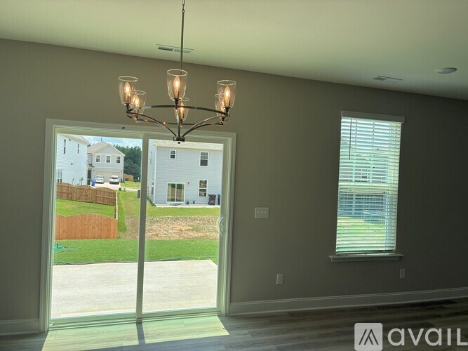 A room with a chandelier, a window, and a view of a house across the street.