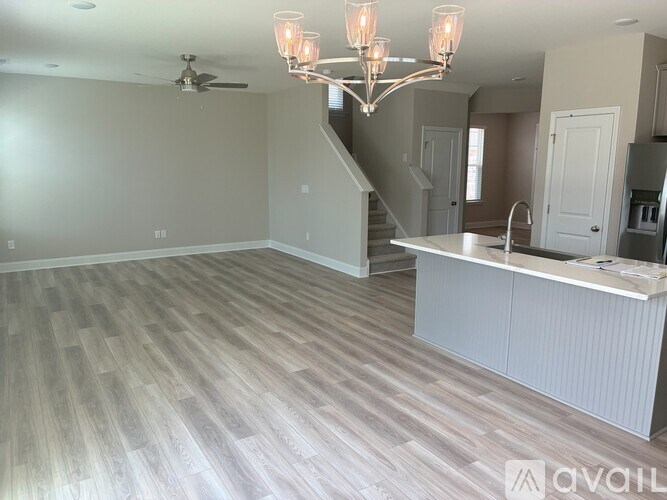 A spacious room with a staircase and a chandelier.