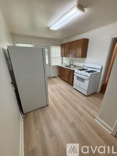 A kitchen with a white fridge, stove and wooden floors.