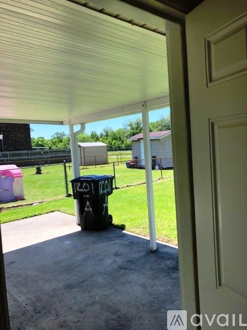 A black trash can with a white label on it is in the foreground of a patio area.