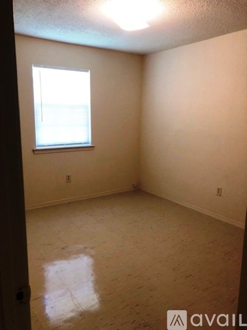 A room with a window and a wooden floor.