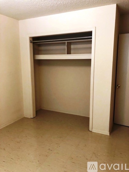 A small white closet with a shelf and a door.
