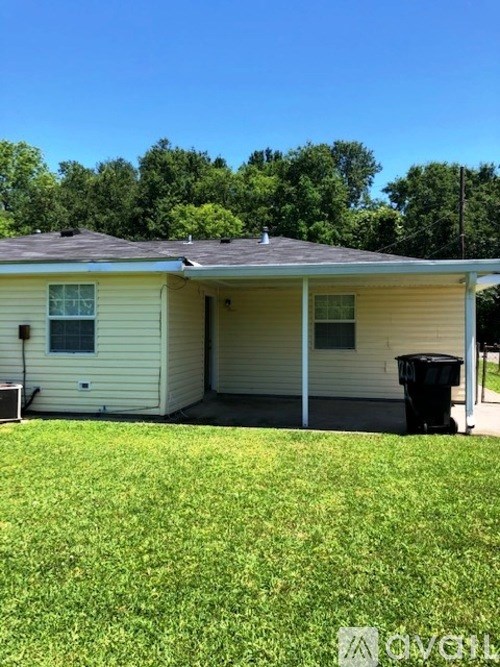 A small house with a brown door and a black trash can in front.