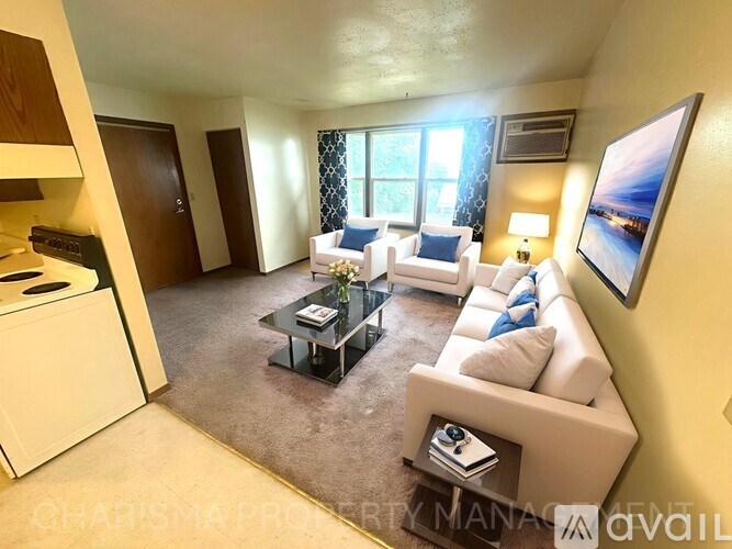 A living room with a white sofa, a black coffee table, and a large painting on the wall.