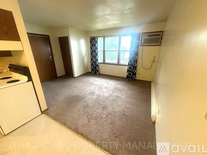 A small, empty room with a window and a curtain.