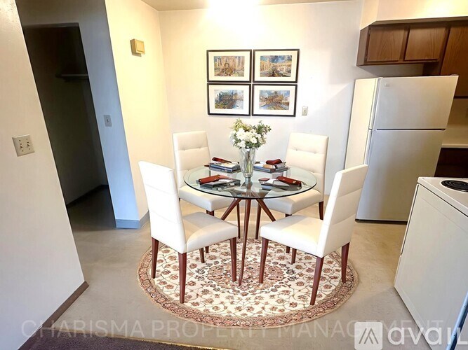 A dining room with a table set for four and a vase of flowers on the table.