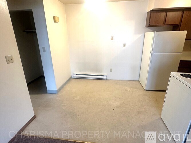 A white refrigerator sits in a kitchen with a white wall and a white door.