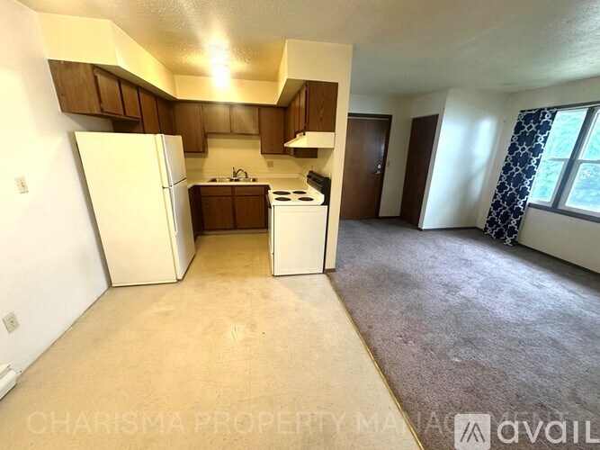 A kitchen area with a refrigerator, stove, and cabinets.