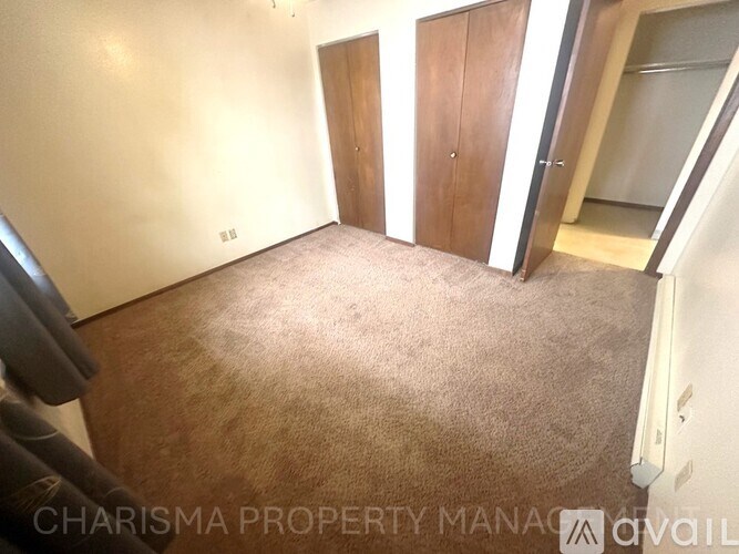 A carpeted room with a door and a wall socket.