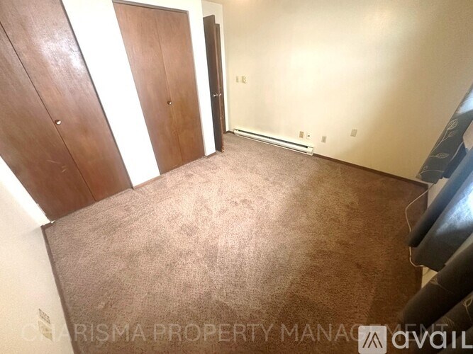A room with carpeted floor and a wall with a door.