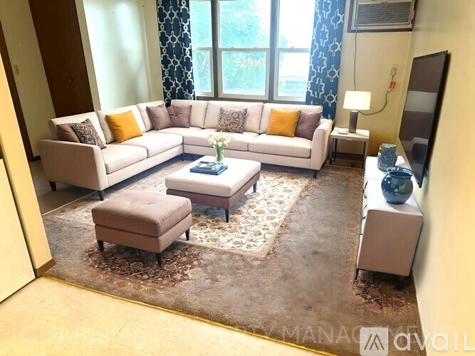 A living room with a white sofa set and a rug.