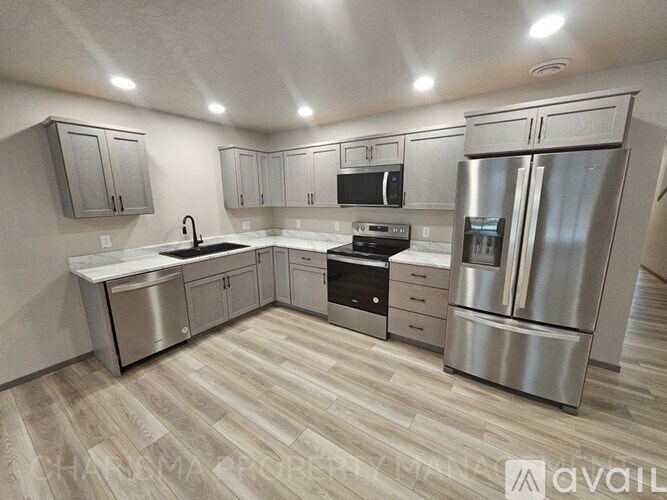 A modern kitchen with stainless steel appliances and wooden flooring.