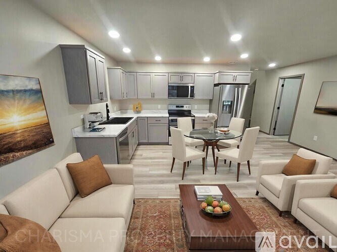 A well-lit, modern kitchen and living room with a dining table set for two.