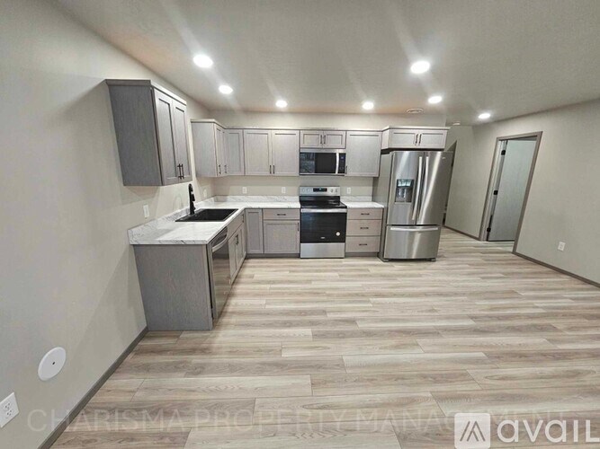 A spacious kitchen with stainless steel appliances and wooden flooring.