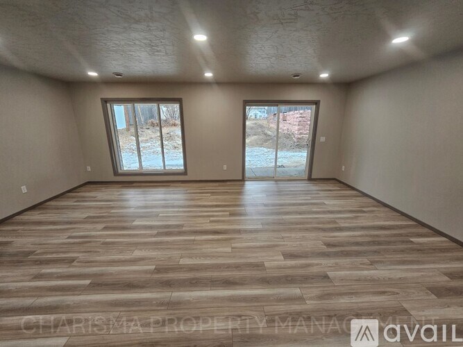 A spacious room with wooden flooring and two sliding glass doors.