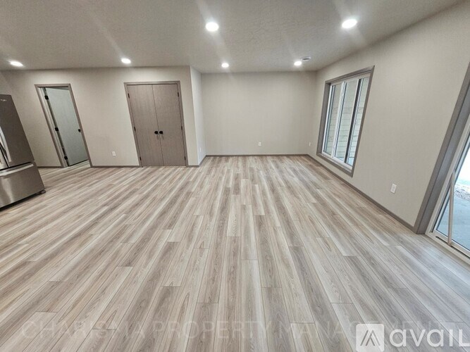 A spacious room with wooden flooring and a large window.