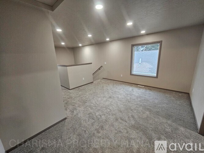 A room with a window and a carpeted floor.