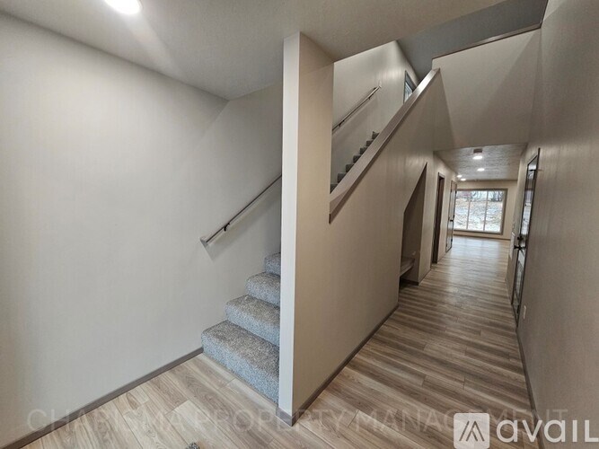 A long hallway with a staircase on the left and a door on the right.