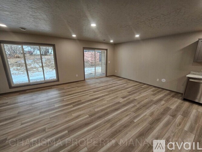 A spacious room with wood flooring and large windows.