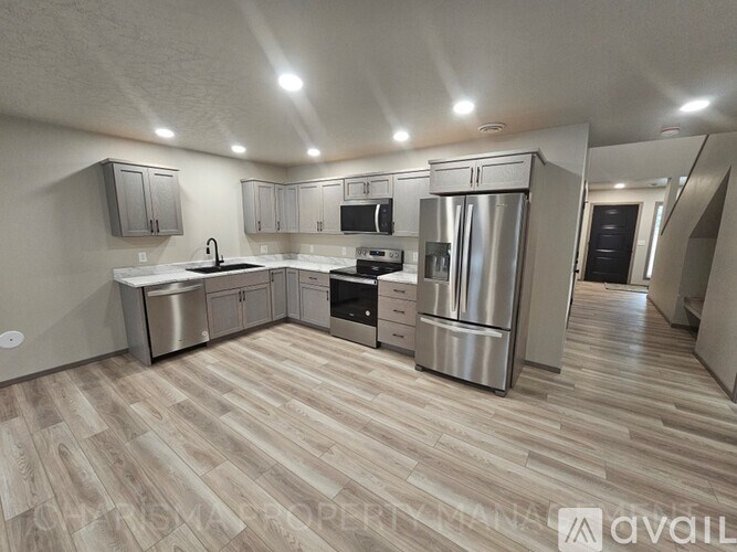 A modern kitchen with wooden flooring and stainless steel appliances.