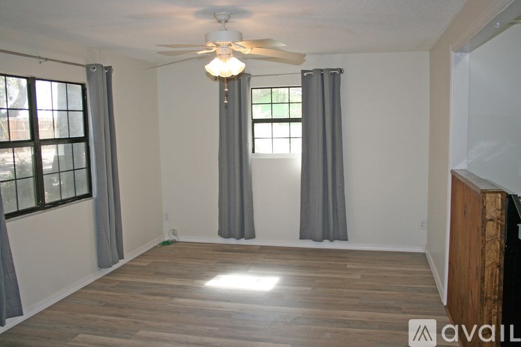 A room with a ceiling fan and a window with curtains.