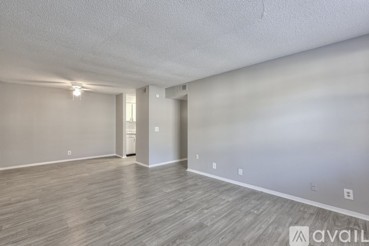 A spacious room with wooden flooring and a white wall.