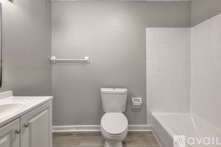A white toilet in a small bathroom with a white tub and sink.