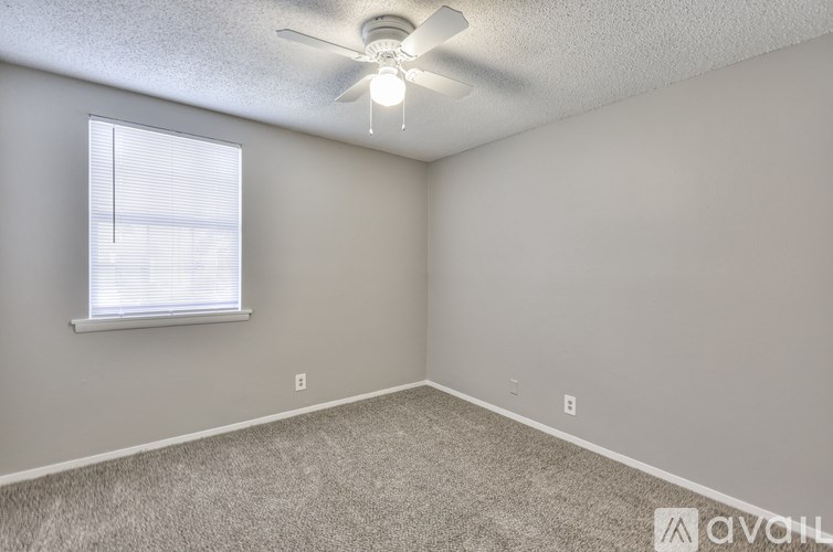 A room with a ceiling fan and a window with blinds.