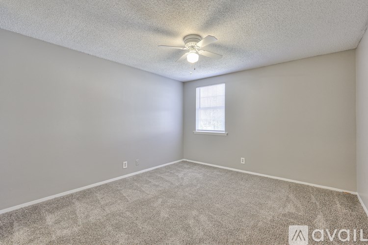 A room with a carpeted floor and a ceiling fan.