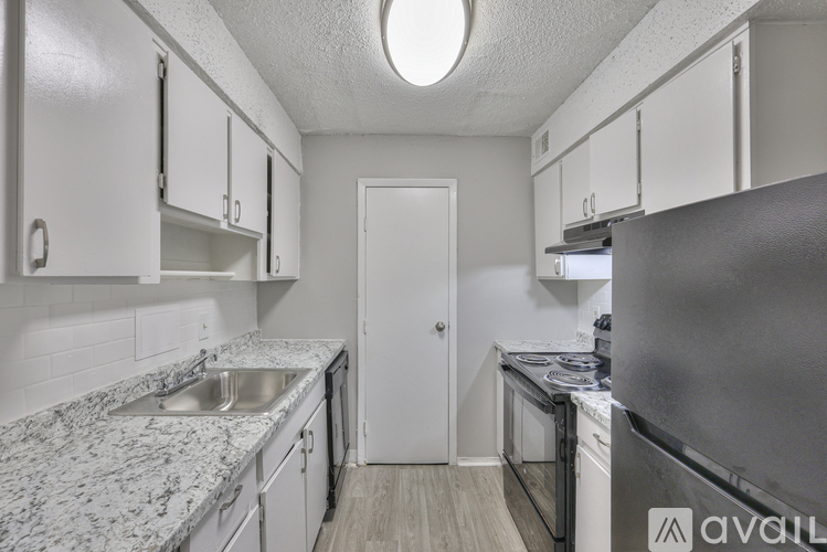A kitchen with a refrigerator, sink, and cabinets.