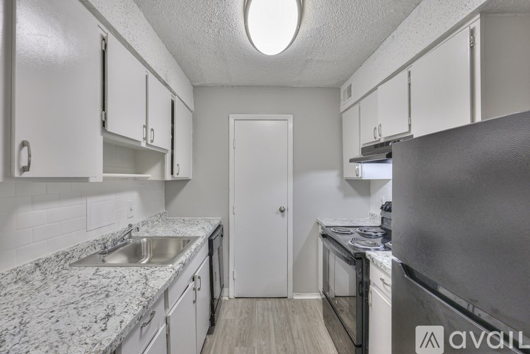 A kitchen with a refrigerator, sink, and cabinets.