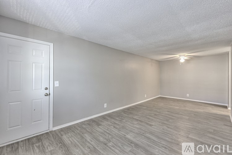 A room with a white door and grey flooring.