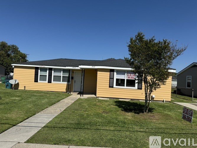 A house with a yellow siding and a sign that says "For Sale" is shown.