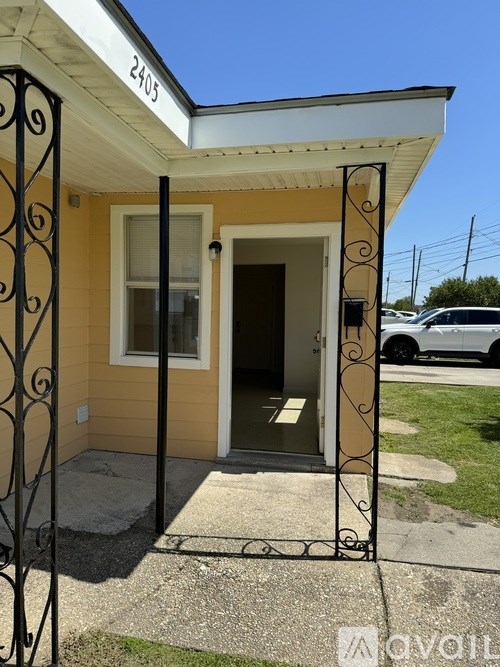 A yellow house with a white door and a black wrought iron gate.
