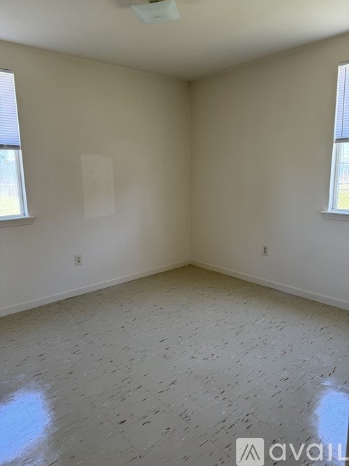A room with a tiled floor and two windows.