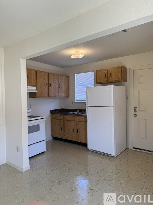 A kitchen with white appliances and wooden cabinets.