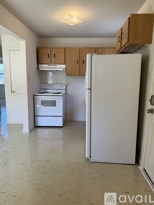 A kitchen with white appliances and wooden cabinets.