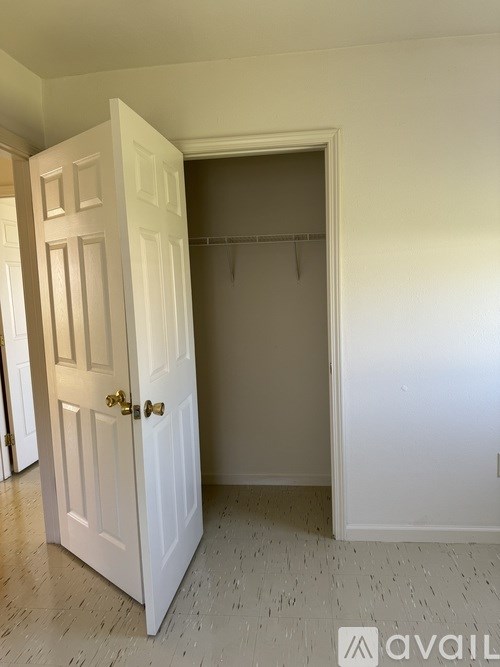 A white door is open to a room with a coat hanger.
