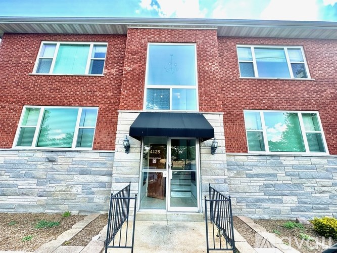 A red brick building with a black awning and a stone facade.