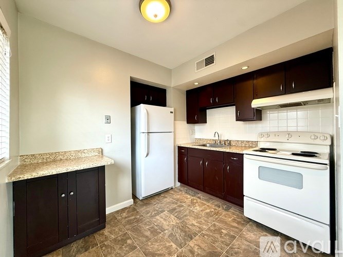 A kitchen with a white refrigerator, white oven, and brown cabinets.