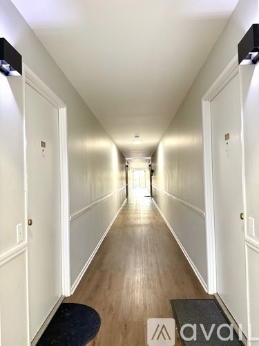 A long hallway with white walls and wood flooring.